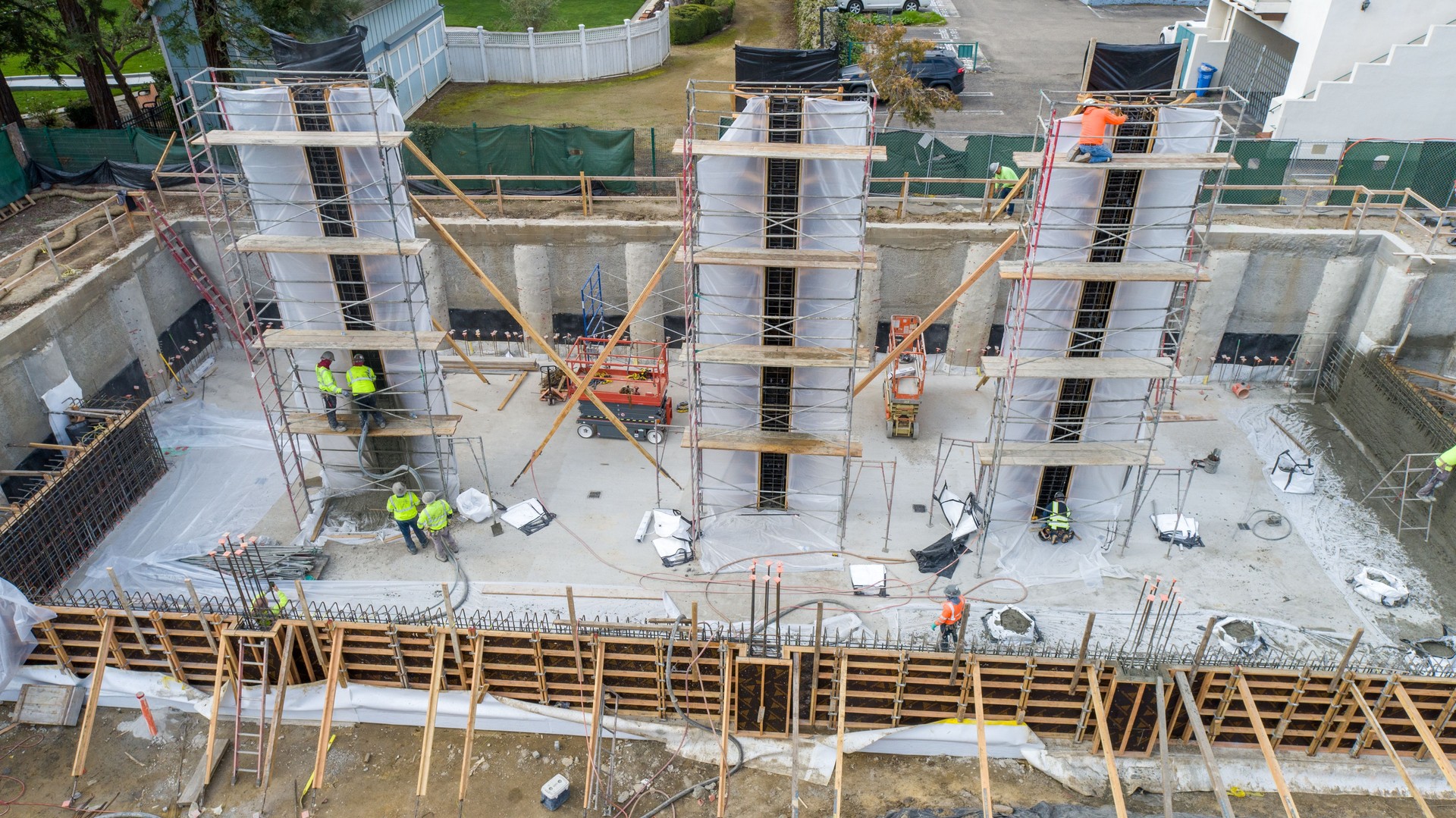 Construction site with tall columns being filled with concrete. Construction workers up on scaffolding
